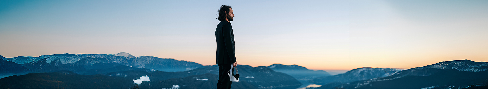 Man holding a virtual reality headset in a mountainous, snowy landscape